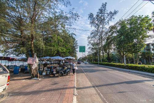 a person standing on the side of a street with a market at Sea View Residence in Cha Am