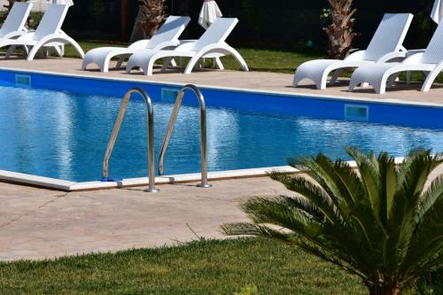 a row of white chairs next to a swimming pool at La Terra Nostra in Korinthos