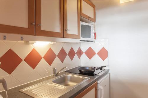 a small kitchen with a sink and a microwave at Résidence Pierre & Vacances Les Combes in Les Menuires