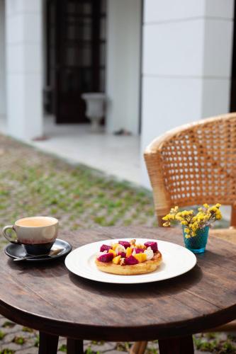 a pastry on a plate on a table with a cup of coffee at Elliebum Boutique Hotel in Chiang Mai