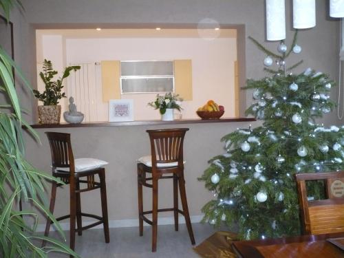 a christmas tree in a living room with two chairs and a bar at Appartement Le Jardin in Lingolsheim