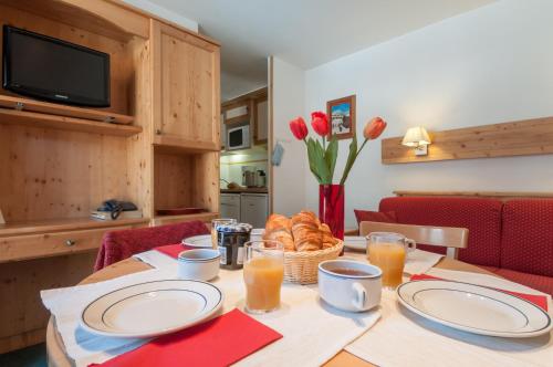 a table with plates and a basket of bread on it at Résidence Pierre & Vacances Le Peillon in Méribel