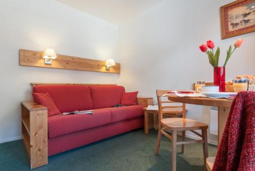 a living room with a red couch and a table at Résidence Pierre & Vacances Le Peillon in Méribel