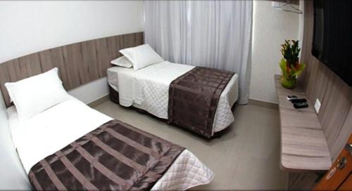 a hotel room with two beds and a bench at Hotel Conexão Pampulha in Belo Horizonte