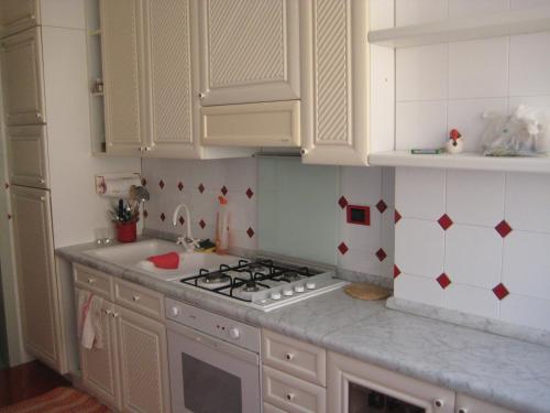 La cuisine est équipée de placards blancs et d'un four avec plaques de cuisson. dans l'établissement A' moglie del comandante, à Gaète