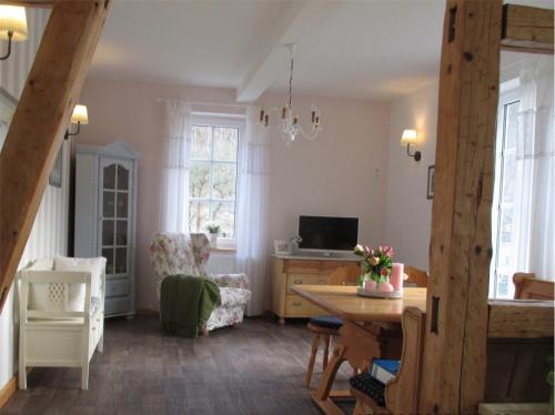 a living room with a table and a chair and a television at Ferienhaus Landliebe Liebenstein in Liebenstein