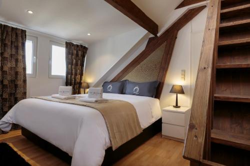 Un dormitorio con una gran cama blanca y suelos de madera. en The Queen Luxury Apartments - Villa Medici, en Luxemburgo