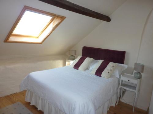 a bedroom with a white bed and a window at Lavender Cottage in Chézelles