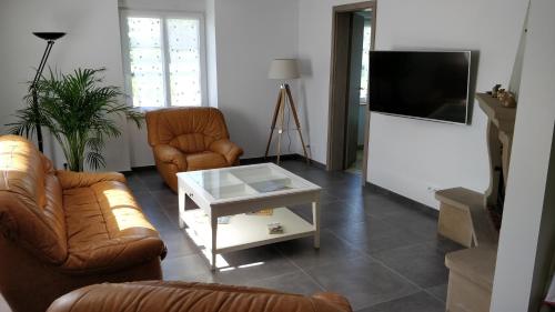 sala de estar con 2 sillas de cuero y TV en Maison des écluses Strasbourg F3 90m2 Jacuzzi Climatisation en Estrasburgo