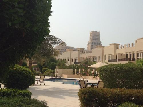un complexe avec une piscine, des chaises et un bâtiment dans l'établissement Townhouse Ras al Khaimah, à Ras al Khaimah