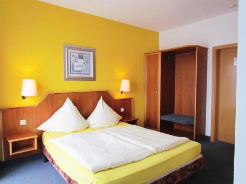 a bedroom with a bed and a yellow wall at Hotel Seeblick in Saalburg