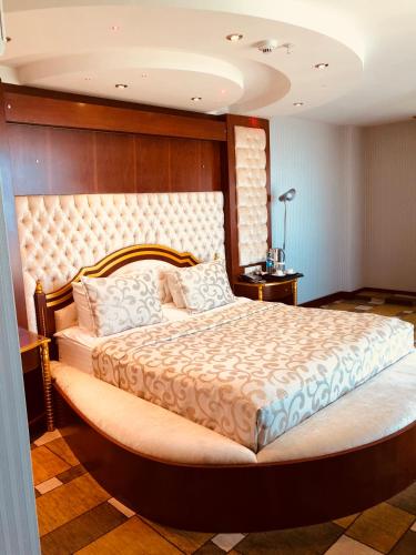 a bedroom with a large bed with a wooden headboard at Grand Amisos Hotel in Samsun