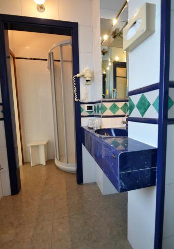 a bathroom with a blue sink and a mirror at Hotel Posta in Cecina
