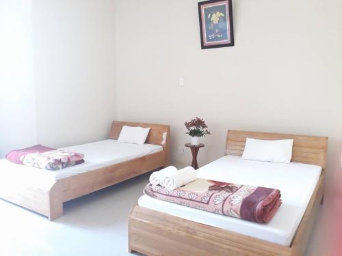 two beds in a room with white walls at Tic Guest House in Liên Trì (3)