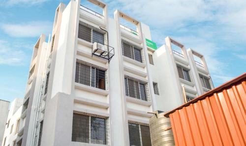 a white building with an orange fence in front of it at Treebo Trend Naunidh Suites in Pune