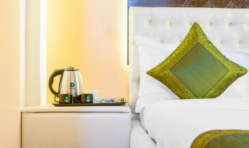 a bed with a coffee maker on a night stand next to a bed at Treebo Naunidh Suites in Pune