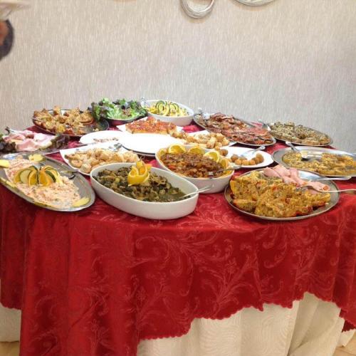 a table with many plates of food on a red table cloth at Sammartano Hotels in Marsala