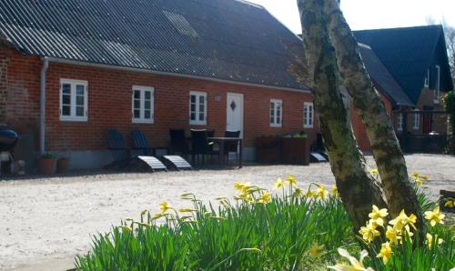 a red brick house with yellow flowers in front of it at Adventure Park Apartments in Ringkøbing