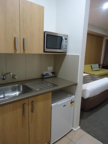 a kitchen with a sink, microwave and refrigerator at Albury Regent Motel in Albury