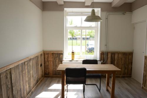 a dining room with a wooden table and a window at Het Wilgenhoekske in Serooskerke