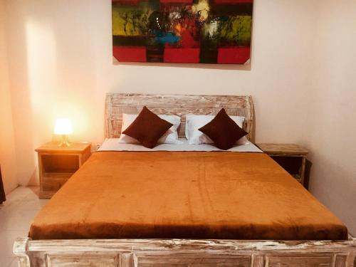 a bedroom with a wooden bed with two pillows at Jordan Guest House in Uluwatu