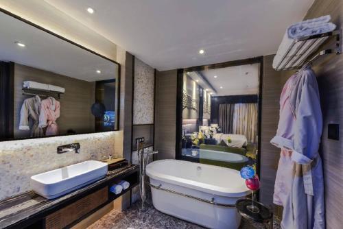 uma casa de banho com um espelho grande, uma banheira e um lavatório. em Braira Al Dammam em Dammam