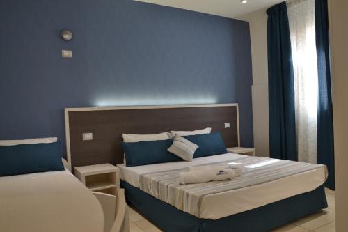 1 dormitorio con 2 camas y paredes azules en Affittacamere Torre Lapillo, en Torre Lapillo