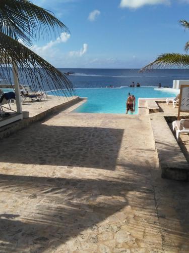 a man standing in a swimming pool next to the ocean at Habitacion en Sol Dominicus solo adultos in Bayahibe