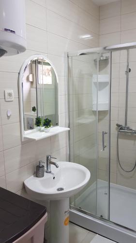 a white bathroom with a sink and a shower at Lux Apartment Vidovic in Rafailovici