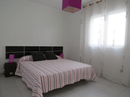 a white bedroom with a bed with a striped blanket at Puig rom 106 in Roses