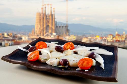 a plate of food with tomatoes and onions on a table at Hotel Royal Passeig de Gracia in Barcelona