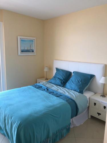 - une chambre avec un lit bleu et 2 tables de chevet dans l'établissement Le Fourneau beach, à Fréjus
