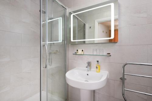 y baño con lavabo y ducha con espejo. en Acorn House, en Keswick