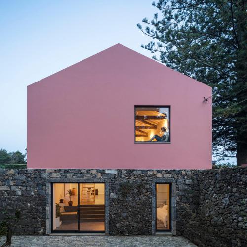 a pink house with a stone wall at Pelago Houses in Ponta Delgada
