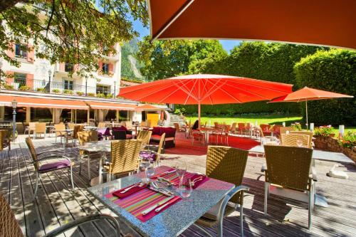 a table and chairs with red umbrellas on a patio at Aiguille du Midi - Hôtel & Restaurant in Chamonix-Mont-Blanc