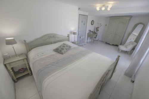 a white bedroom with a large bed and a table at Domaine La Garenne in Reilhaguet