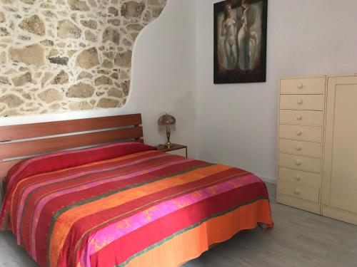 1 dormitorio con cama y pared de piedra en B&B Tredomus, en Tresnuraghes