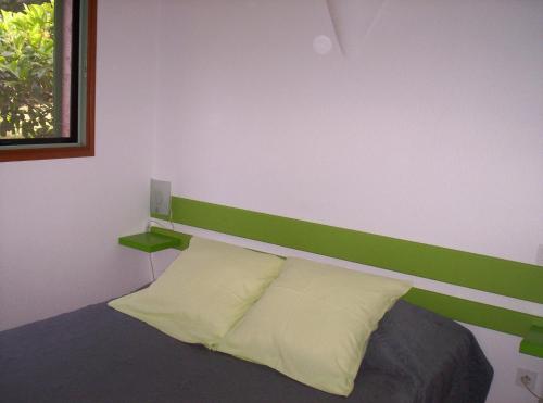 ポルト・ヴェッキオにあるRésidence Les Aulnesのベッド1台(緑のヘッドボード、枕2つ付)
