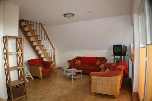 a living room with red couches and a staircase at Nickelshus-Whg-Lars in Sankt Peter-Ording