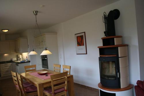 a kitchen and dining room with a table and a fireplace at Nickelshus-Whg-Birte in Sankt Peter-Ording