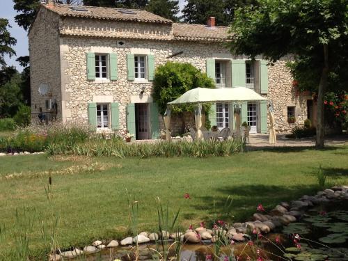 an old stone house with a pond in front of it at Le Mas d'Hermès in Plan-dʼOrgon
