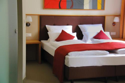 Schlafzimmer mit einem Bett mit roten und weißen Kissen in der Unterkunft Landhotel-Neunburg in Neunburg vorm Wald