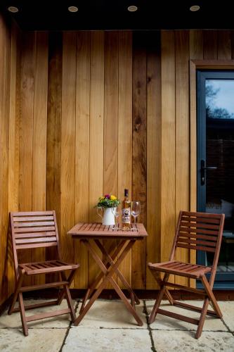 two chairs and a table in front of a wooden wall at The Thomas Lord in West Meon