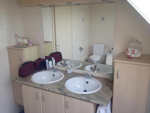 een badkamer met 3 wastafels en een toilet bij didi logement in Westerlo