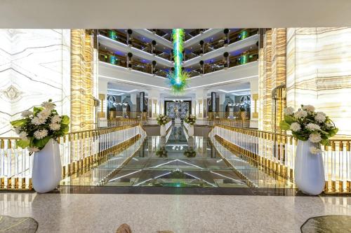 a lobby with a staircase with flowers in white vases at Granada Luxury Belek - Family Kids Concept in Belek