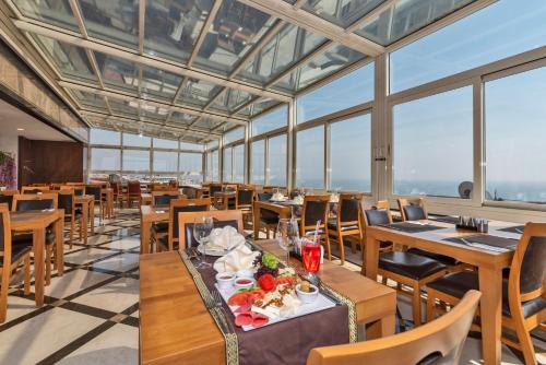 a restaurant with wooden tables and chairs and windows at Piya Sport Hotel in Istanbul