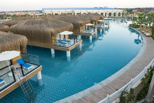 an overhead view of a resort pool with chairs and thatch roofs at Granada Luxury Belek - Family Kids Concept in Belek