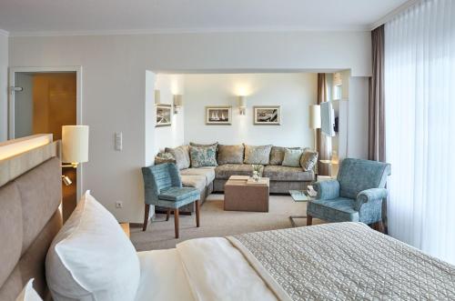 a hotel room with a bed and a couch and chairs at Hotel Strandidyll in Grömitz