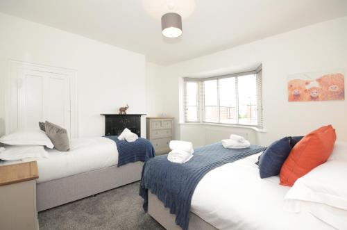 twee bedden in een kamer met witte muren bij York Boutique House- spacious & stylish with free parking in York