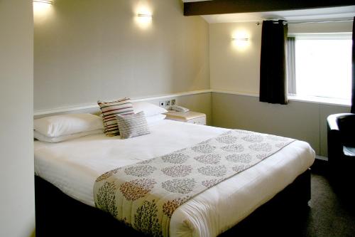 a bedroom with a large bed with pillows and a window at Damon’s Hotel in Lincoln